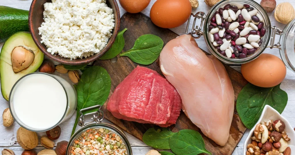 Különböző fehérjeforrások egy asztalon: tojás, csirkemell, hüvelyesek, tejtermékek és magvak, kiegyensúlyozott étkezés és életmódváltás szemléltetésére.