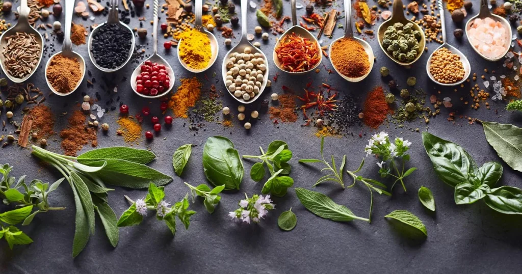 Különféle fűszerek és friss zöldfűszerek egy asztalon, egyszerű ízesítés és tudatos étkezés szemléltetésére.